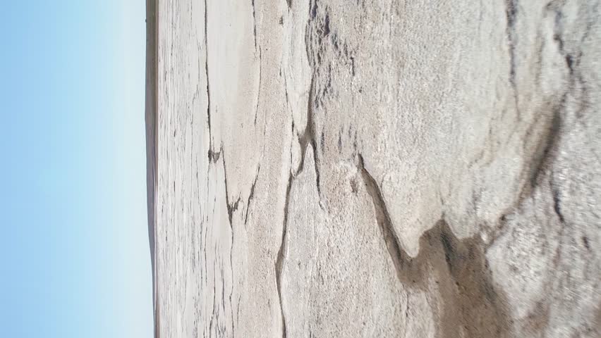 Salt Lake with deposits of white salt and cracks. Aerial view. Vertical Video