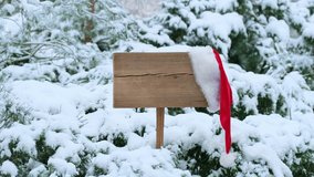 Santa hat on wooden road sign, nature background with pinetrees and snowy forest. Concept of Christmas holiday and happy New Year. Winter nature. Signboard with red hat - Powered by Shutterstock - Get 15% off with code: PIKWIZARD15