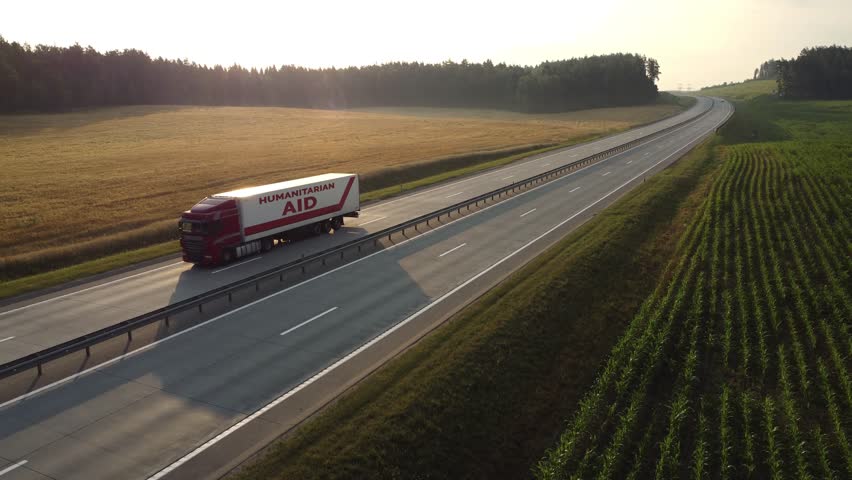 Aerial view: Truck with trailer, loaded with humanitarian aid for people affected by war, natural disasters. Transportation of medical aid, food aid, basic necessities for Ukrainian refugees. 4k 