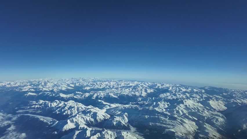 The snowed Alps. Breathtaking aerial view, as seen by the pilots of an airplane flying at 10000m high in a bright and splendid winter morning.