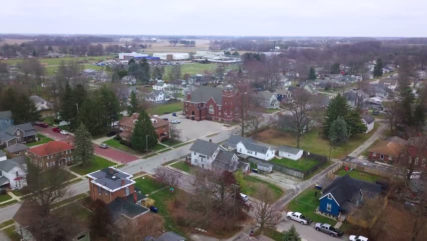 Aerial view over Sheridan town autumnal neighbourhood in Hamilton county Indiana towards Methodist church