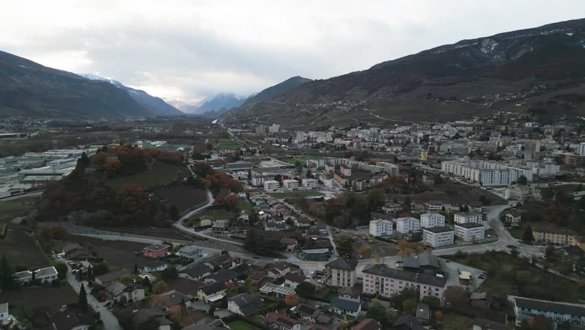 Flight over a small town in the Swiss mountains. Siders in the canton of Valais with snow covered mountains in winter