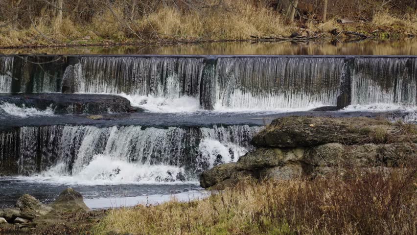 Fast flowing waterfall cascading down multiple levels into rocky river wilderness