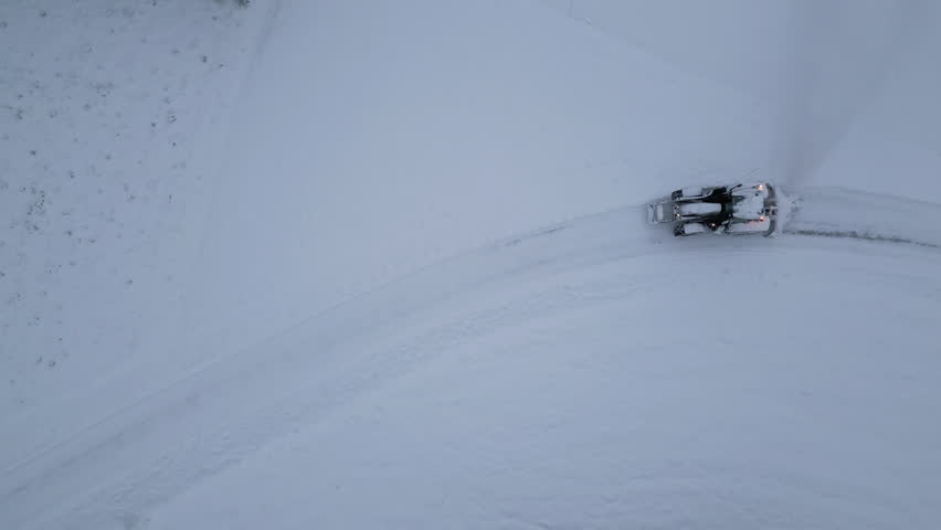 Aerial view of tractor clearing road after snow blizzard in arctic winter landcape