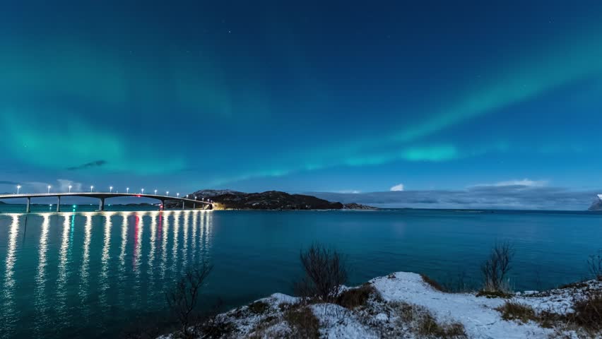 time lapse of northern lights over sommaroy village on island and bridge during winter night in norway