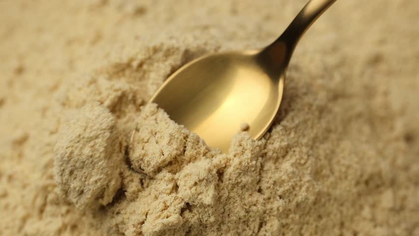 Ground ginger powder in spoon. Condiment or dietary supplement