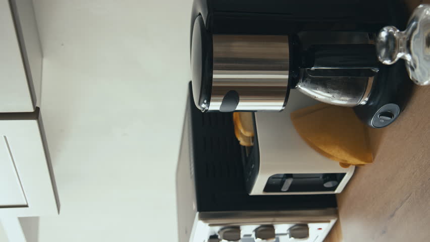 Vertical stab side shot of unrecognizable male hands loading coffeemaker with ground coffee and turning it on in modern home kitchen Royalty-Free Stock Footage #3403857247