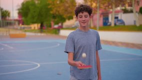 Teenager holding table tennis racket and bouncing ping pong ball. Slow motion film clip with sport equipment