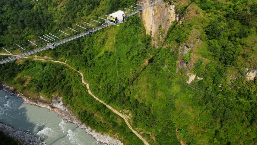 Aerial top down shot of bungee jumping on Bridge in Nepal at sunset time - Cinematic drone flight over river
