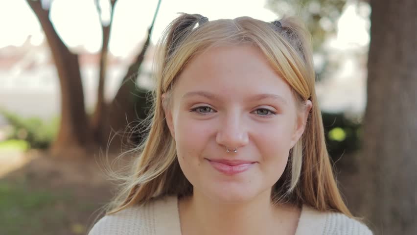 Close up portrait of smiling teenage girl with nose ring sitting in park outdoors. Happy childhood