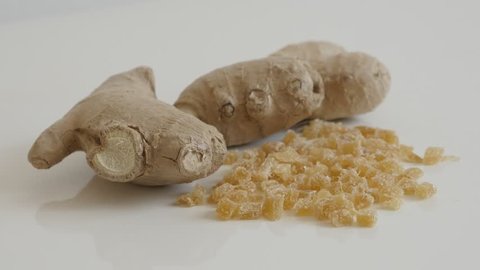 Raw and candied ginger root on the table slow tilt 4K 2160p 30fps UltraHD footage - Fresh Zingiber officinale and crystallized cubes 3840X2160 UHD tilting video