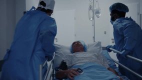 Surgeons transport senior patient down the clinic corridor to operation room. Medics open doors for other doctors with patient. Old man lies on gurney under drip and with pulse oximeter on his finger. - Powered by Shutterstock - Get 15% off with code: PIKWIZARD15