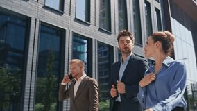 Office coworkers strolling street smiling enjoying communication. Successful three business people talking sharing news on go. Confident businessman calling cellphone walking with colleagues outdoors. - Powered by Shutterstock - Get 15% off with code: PIKWIZARD15