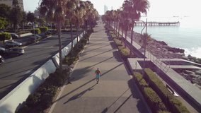 4K drone footage of running man on promenade, Cyprus. 4K drone video of an athlete running near the sea on a sunny morning, Limassol, Cyprus.