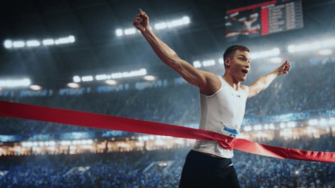 Fit Athlete Finishing a Sprint Run at a Crowded Arena with Cheering Spectators. Young Man Crossing the Finish Line with a Red Ribbon. Cinematic Super Slow Motion Sports Footage Stock Video