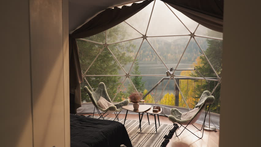 Modern glamping house with glass terrace. Relaxation place equipped with cozy furniture for lunch breaks to enjoy lake view. Glamping cottage for tourists