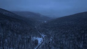 Beautiful aerial drone video footage of a mountain road through the Appalachian Mountains covered in snow at night during evening