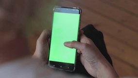 Chroma key mock-up on smartphone in hand. Woman holds mobile phone and swipes photos or pictures. Use green screen for copy space closeup.