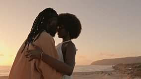 Concept of Love and passion, a stunning black woman in a white dress embraces a handsome African man with dreadlocks on the beach at sunset, sharing a moment of intense connection - Powered by Shutterstock - Get 15% off with code: PIKWIZARD15