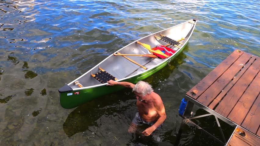 A man bringing his canoe ashore after a satisfying canoe trip.