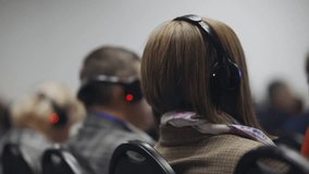 People wearing translation headphones at an international conference, listening to translation on headphones. close-up of people wearing headphones for simultaneous translation during a conference.