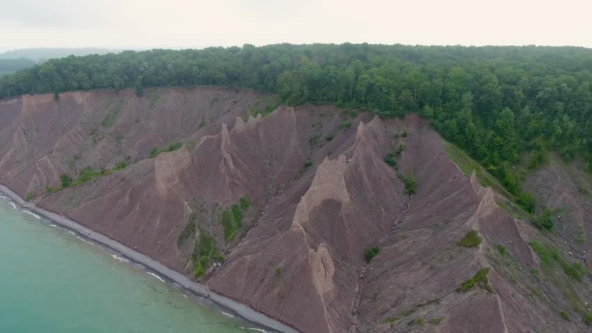 A 4K drone shot over the large clay formations of Chimney Bluffs State Park, on the water