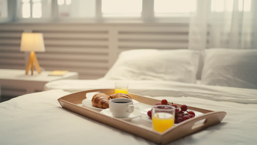 A tray with coffee, pastry and fruit standing on bed, breakfast in a cozy hotel