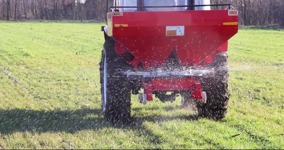 Farmer with agricultural machinery fertilizing wheat field in spring time, slow motion. Spreading synthetic fertilizer Royalty-Free Stock Footage #3404869485