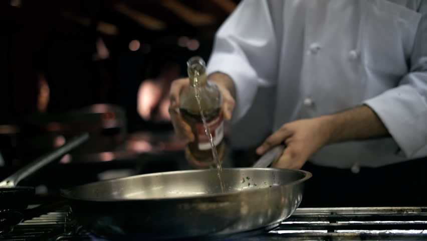 Chef pours alcohol into a pan to flambé food Royalty-Free Stock Footage #34048834