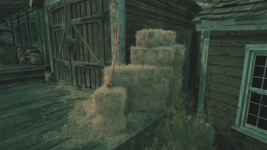 A barn with hay bales in front of it