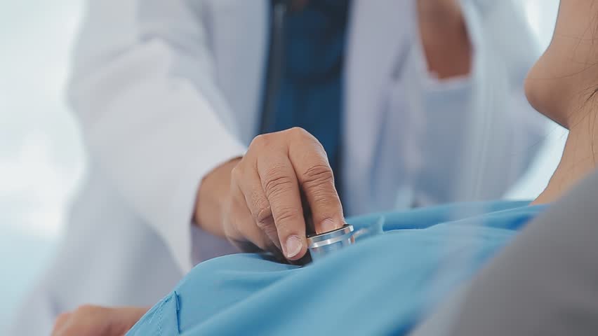 Close up of Female Doctor using stethoscope putting beat heart diagnose with patient in examination room at a hospital, check-up body, Medical and Health Care Concept.