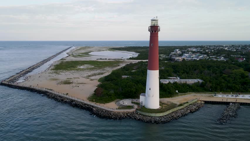 A 4K drone shot of the Barnegat Lighthouse, located on the northern tip of Long Beach Island in Ocean County, New Jersey, U.S.A. The camera rises and rotates left around the lighthouse.