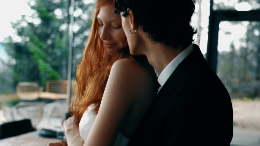 Fairy-tale wedding couple posing in a stylish house with panoramic windows and mountain views. Red-haired bride posing with the groom. Wedding concept Royalty-Free Stock Footage #3405102885