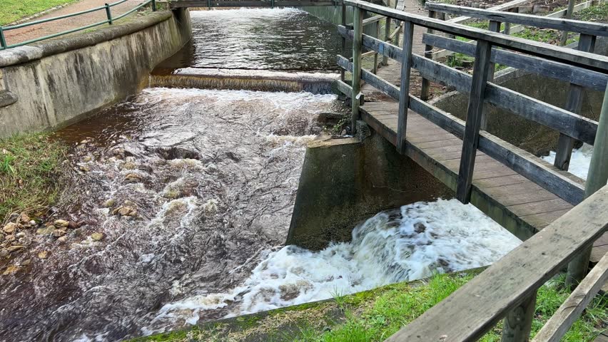 Two stormwater rivers meeting to a point with wood foot bridges crossing over it