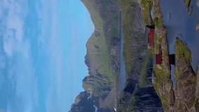 A flight over a lake and a small house in the beautiful mountains of the Lofoten Islands. Munkebu is a famous place, popular for tourists, Norway, vertical footage