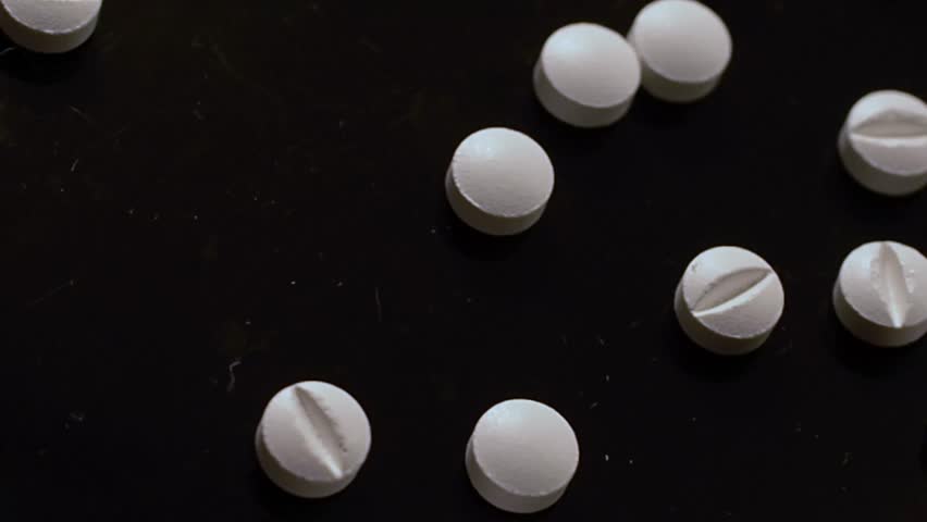 Drug addiction - white pills sprinkled on a black surface and handled illegally Royalty-Free Stock Footage #3405200815