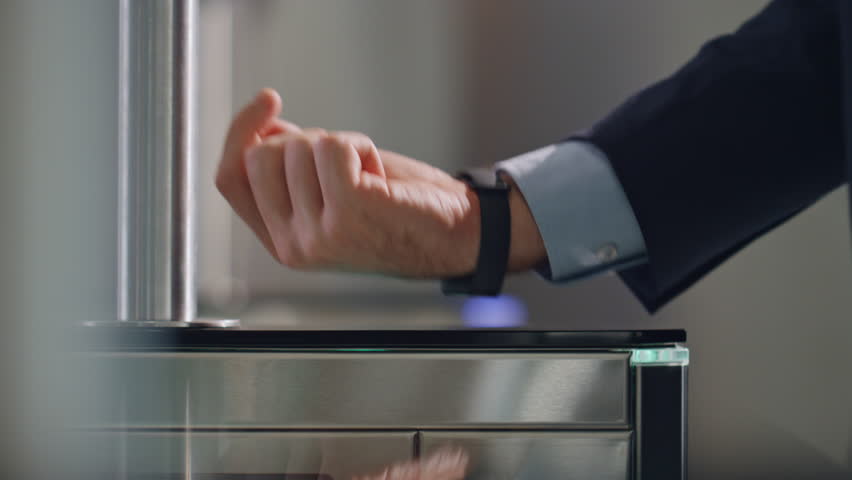 Hand with smartwatch touching sensor control panel unlocking office turnstile close up. Unrecognizable businessman using digital watch passing identification security control in business center.