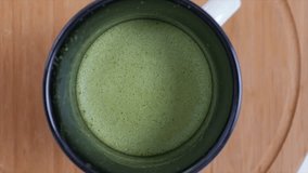 Pouring milk into green matcha tea, slow motion video