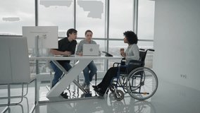 Person at workplace in wheelchair. African american businesswoman sitting in wheelchair brainstorming at table with other colleagues. Teamwork in the office.People and business concept. - Powered by Shutterstock - Get 15% off with code: PIKWIZARD15