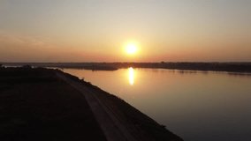 Video 4k footage of aerial drone shot over grass field and Mekong river at beautiful sunset in Thailand.