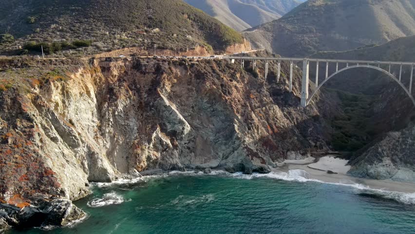 Aerial of the rugged coastline of Big Sur California. The Pacific Coast Highway and the famous Bixby Creek Bridge can be seen. Royalty-Free Stock Footage #3405486411