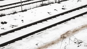 single railway track running diagonally across the frame, with a background of snow-covered ground and sparse winter vegetation