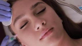 A cosmetologist performs a procedure of rejuvenating injections to smooth out wrinkles. Vertical video.