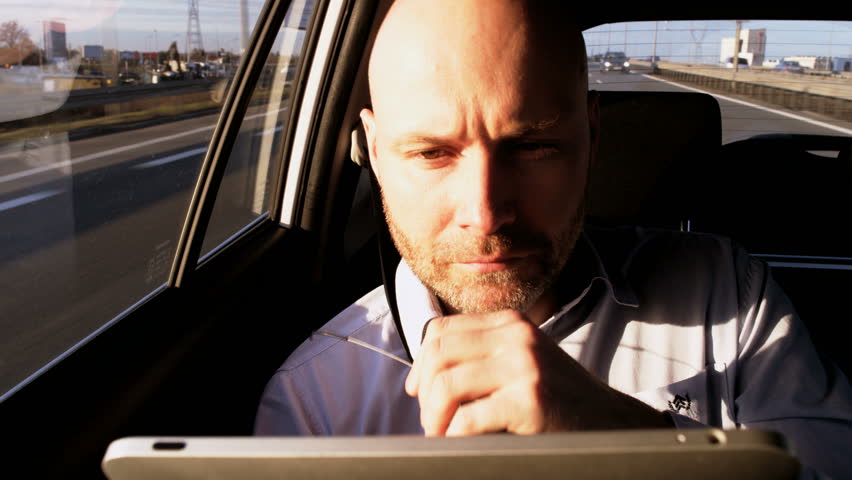 Man Holding a Handle in his Mouth While Using a Tablet