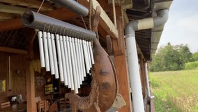 4k video footage of Aluminum wind Chimes hangs on traditional javanese house ceilings or wall with wooden house interior backgrounds. Close-up hanging metalic wind chime during the day.