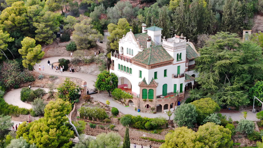 Aerial drone view of Park Guell. Antoni Gaudi architecture. A lot of greenery around, tourists, Barcelona, Spain