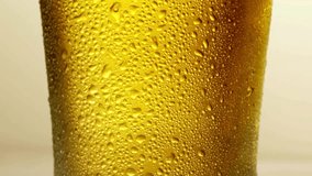 Beer is pouring from the top into the glass forming waves Anamorphic close up beer pouring from top Cold beer pouring in the cup in slow motion drunk