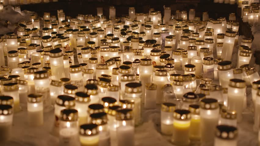 Candle lights on graves and tombstones at a cemetery. Lit candles illuminate the graves at a Christian cemetery at night. In the memory of victims of the war in Ukraine Royalty-Free Stock Footage #3405806505