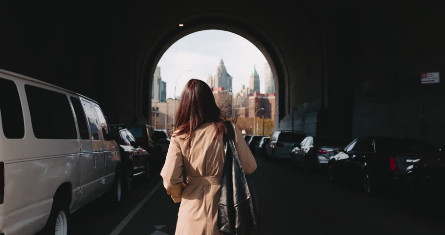 Rear view of stylish brunette female walking under the tunnel towards urban views of New York Royalty-Free Stock Footage #3405826227