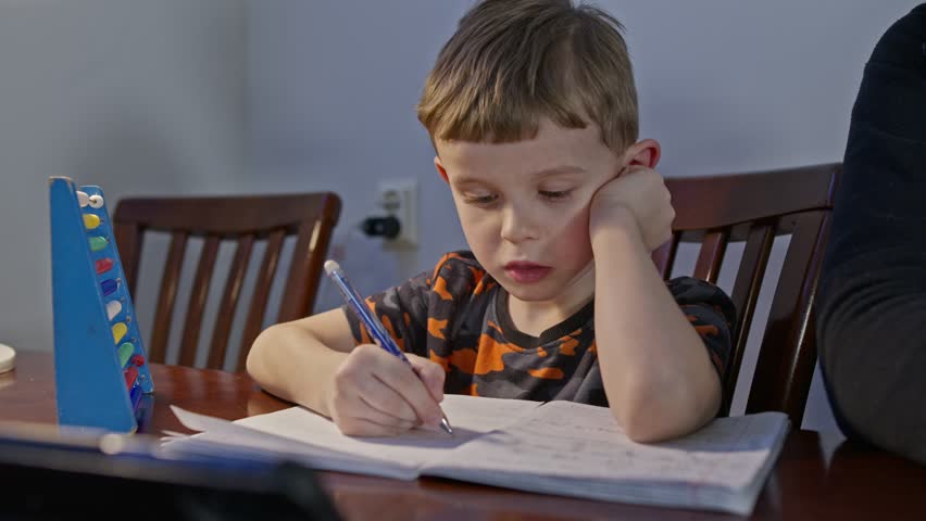 A preschool boy child studying lesson writing with pen. Serious kid primary class student write exercise homework home learning education Royalty-Free Stock Footage #3405843047